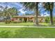 Charming single-story home featuring lush landscaping, a manicured lawn, and a welcoming facade under a blue sky at 2504 Oak Landing Dr, Brandon, FL 33511