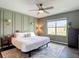 Bedroom featuring panel accent wall, ceiling fan, large window, and neutral decor; a calm, inviting atmosphere at 34033 Jasper Stone Dr, Wesley Chapel, FL 33543