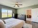 A sunlit bedroom features a ceiling fan, large window, and a neutral-toned color palette and wood-look floors at 34033 Jasper Stone Dr, Wesley Chapel, FL 33543