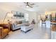 Cozy living room featuring a ceiling fan, gray sofa, and access to the kitchen at 34033 Jasper Stone Dr, Wesley Chapel, FL 33543