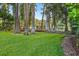 A backyard view shows a wooden deck overlooking the water, surrounded by mature trees and lush green grass at 3620 Little Rd, Lutz, FL 33548