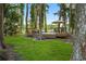 This backyard view showcases a wooden deck with seating, surrounded by mature trees and overlooking the water at 3620 Little Rd, Lutz, FL 33548