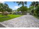 Paver driveway leading to a well-maintained one story home surrounded by mature trees and landscaping at 3620 Little Rd, Lutz, FL 33548