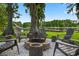 Lakeside backyard has a custom fire pit surrounded by chairs, offering a relaxing space to unwind at 3620 Little Rd, Lutz, FL 33548