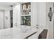 Bright kitchen with sleek white cabinetry, open shelving, and marble countertop at 3620 Little Rd, Lutz, FL 33548