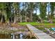 Scenic lakeside view showcasing a private dock, outdoor seating, and lush landscaping at 3620 Little Rd, Lutz, FL 33548
