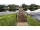 Scenic view of lake with dock, grassy shoreline, lush trees, and serene water, perfect for relaxation at 3810 N Oak Dr # N31, Tampa, FL 33611