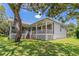 Rear exterior view showcases a white home, large yard, and outdoor patio with lattice at 389 Grand Bay Dr, Palm Harbor, FL 34683