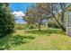 Spacious backyard features mature trees and lush green grass, offering ample space for outdoor activities at 389 Grand Bay Dr, Palm Harbor, FL 34683