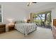 Bright bedroom with neutral carpet, ceiling fan and sliding doors leading to a screened patio at 389 Grand Bay Dr, Palm Harbor, FL 34683