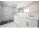 This bathroom features a glass shower, marble floors, and a double sink with white cabinets and a large mirror at 4015 Overlook Ne Dr, St Petersburg, FL 33703