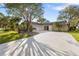 Charming single-story home featuring a circular driveway, mature trees, and a well-manicured lawn at 4157 Marine Pkwy, New Port Richey, FL 34652