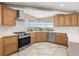 Well-equipped kitchen with stainless steel appliances and natural wood cabinets, and a corner sink overlooking the outdoors at 4157 Marine Pkwy, New Port Richey, FL 34652