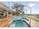 Inviting screened-in pool with a connected spa, surrounded by a brick patio at 4157 Marine Pkwy, New Port Richey, FL 34652