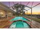 Beautiful screened in pool with spa and brick patio at sunset at 4157 Marine Pkwy, New Port Richey, FL 34652