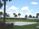 Sandy volleyball court with net, lush greenery, and palm trees on a sunny day at 4957 Seafoam Trl, Bradenton, FL 34211