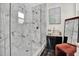 Modern shower with sleek glass enclosure and marble-look walls, with black cabinet next to a velvet bench at 5006 W Idaho St, Tampa, FL 33616