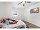 Bedroom with ceiling fan, window with blinds, wood-look flooring, and wall-mounted television at 5055 9Th St, Zephyrhills, FL 33542