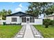 Charming single-story home boasts a screened-in porch, manicured lawn, and inviting walkway at 5055 9Th St, Zephyrhills, FL 33542