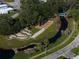 An aerial view shows a mini-golf course next to a bocce ball court and covered dock surrounded by lush landscaping at 5706 Benton St, Zephyrhills, FL 33542