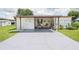 Spacious carport and entrance area with outdoor seating, offering a comfortable and inviting welcome to this cozy home at 5706 Benton St, Zephyrhills, FL 33542