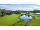 An aerial view displays a verdant golf course with a scenic pond, perfect for outdoor enthusiasts at 5706 Benton St, Zephyrhills, FL 33542