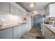 Well-lit kitchen features painted cabinets, modern appliances, and wood-look vinyl flooring at 5706 Benton St, Zephyrhills, FL 33542