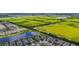 Overhead shot of a neighborhood bordering a field of farmland, pond, and lush trees, capturing nature's tranquility at 6211 Sea Air Dr, Apollo Beach, FL 33572
