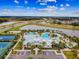 An aerial view of a community pool with tennis courts, clubhouse, and parking near a scenic lake at 6211 Sea Air Dr, Apollo Beach, FL 33572