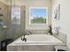 Bright bathroom with a soaking tub, glass enclosed shower, and view of the outdoors at 6211 Sea Air Dr, Apollo Beach, FL 33572