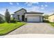 Charming single-story home featuring a stone facade, manicured lawn, and a paved driveway leading to a two-car garage at 6211 Sea Air Dr, Apollo Beach, FL 33572
