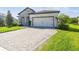 Charming single-story home featuring a stone facade, manicured lawn, and a paved driveway leading to a two-car garage at 6211 Sea Air Dr, Apollo Beach, FL 33572