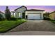 Charming single-story home featuring a stone facade, manicured lawn, and a paved driveway leading to a two-car garage at 6211 Sea Air Dr, Apollo Beach, FL 33572