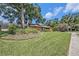 Landscaped front yard showcasing a lovely home with mature trees, green grass, and shrubbery at 6709 Peachtree Dr, Temple Terrace, FL 33617