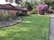 Charming single-story home featuring a well-maintained lawn, mature trees, and colorful landscaping at 6709 Peachtree Dr, Temple Terrace, FL 33617