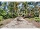 A gravel driveway leads into a property lush with trees and has a wooden swing set at 6924 Valrie Ln, Riverview, FL 33569