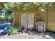 A garage exterior has a door with yellow trim, plants, a window, and trashcans beside the door at 6924 Valrie Ln, Riverview, FL 33569