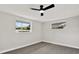 Bedroom with modern gray flooring, two bright windows, neutral walls, and ceiling fan at 7835 Wallaba Ln, New Port Richey, FL 34653