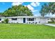 Charming home featuring a manicured lawn, fresh paint, and stylish blue accents against a bright sunny sky at 7835 Wallaba Ln, New Port Richey, FL 34653