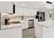 Bright kitchen features stainless appliances, marble backsplash, sleek white cabinets and island with pendant lights at 7835 Wallaba Ln, New Port Richey, FL 34653