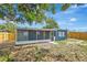 Back view of charming home with fenced-in yard and screened lanai amid lush greenery at 8033 Norwich Dr, Port Richey, FL 34668