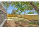 Large backyard with wood fence, mature tree providing shade on a sunny day, and view of lanai at 8033 Norwich Dr, Port Richey, FL 34668