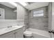 Bathroom features a shower/tub combo, gray tile, white vanity and natural light at 8033 Norwich Dr, Port Richey, FL 34668