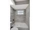 Renovated bathroom with gray tile, shower and tub combo and plenty of natural light at 8033 Norwich Dr, Port Richey, FL 34668
