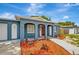 Charming blue single-story home with a red front door, enhanced by arched entryways and tasteful landscaping at 8033 Norwich Dr, Port Richey, FL 34668