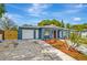Charming blue single-story home with a well-manicured lawn, complemented by a red front door and attached garage at 8033 Norwich Dr, Port Richey, FL 34668
