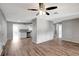 Open living room showcasing wood-look floors, a contemporary ceiling fan, and seamless flow into the kitchen at 8033 Norwich Dr, Port Richey, FL 34668