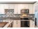 Modern kitchen with white cabinets, stainless appliances, and a tile backsplash at 9016 Water Chestnut Dr, Temple Terrace, FL 33637