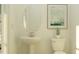 Elegant bathroom with pedestal sink, toilet, oval mirror and framed abstract art for a clean and modern look at 9497 Minnow Ray Dr, Land O Lakes, FL 34638