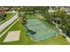 Aerial view of a well-maintained tennis court in a gated community with lush landscaping and a playground nearby at 10409 Glen Willow Ln, Tampa, FL 33647